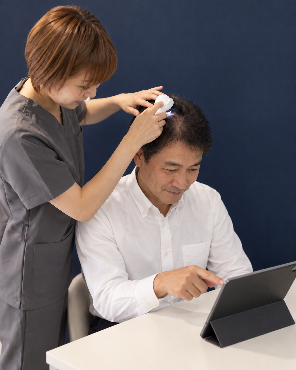 頭皮の画像を見ながら相談する男性と担当者のイメージ